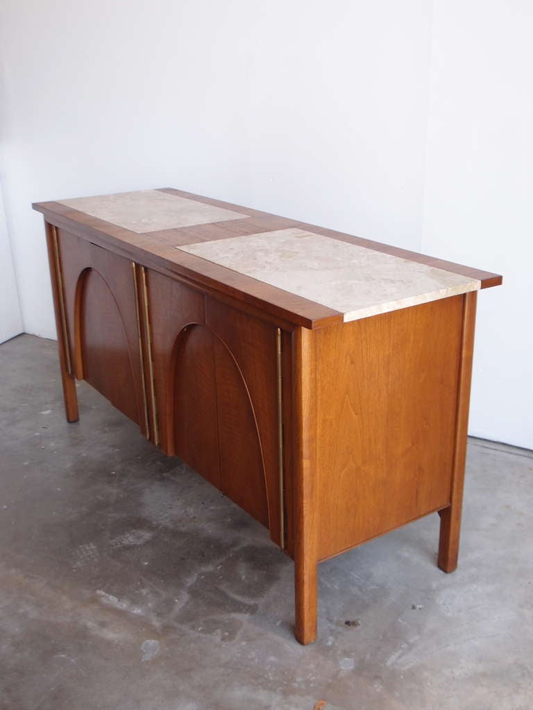 This sculptural mid-century sideboard has three drawers on the left side behind the doors and a shelf on the right hand side.
There are two marble sections on the top which is perfect for entertaining.