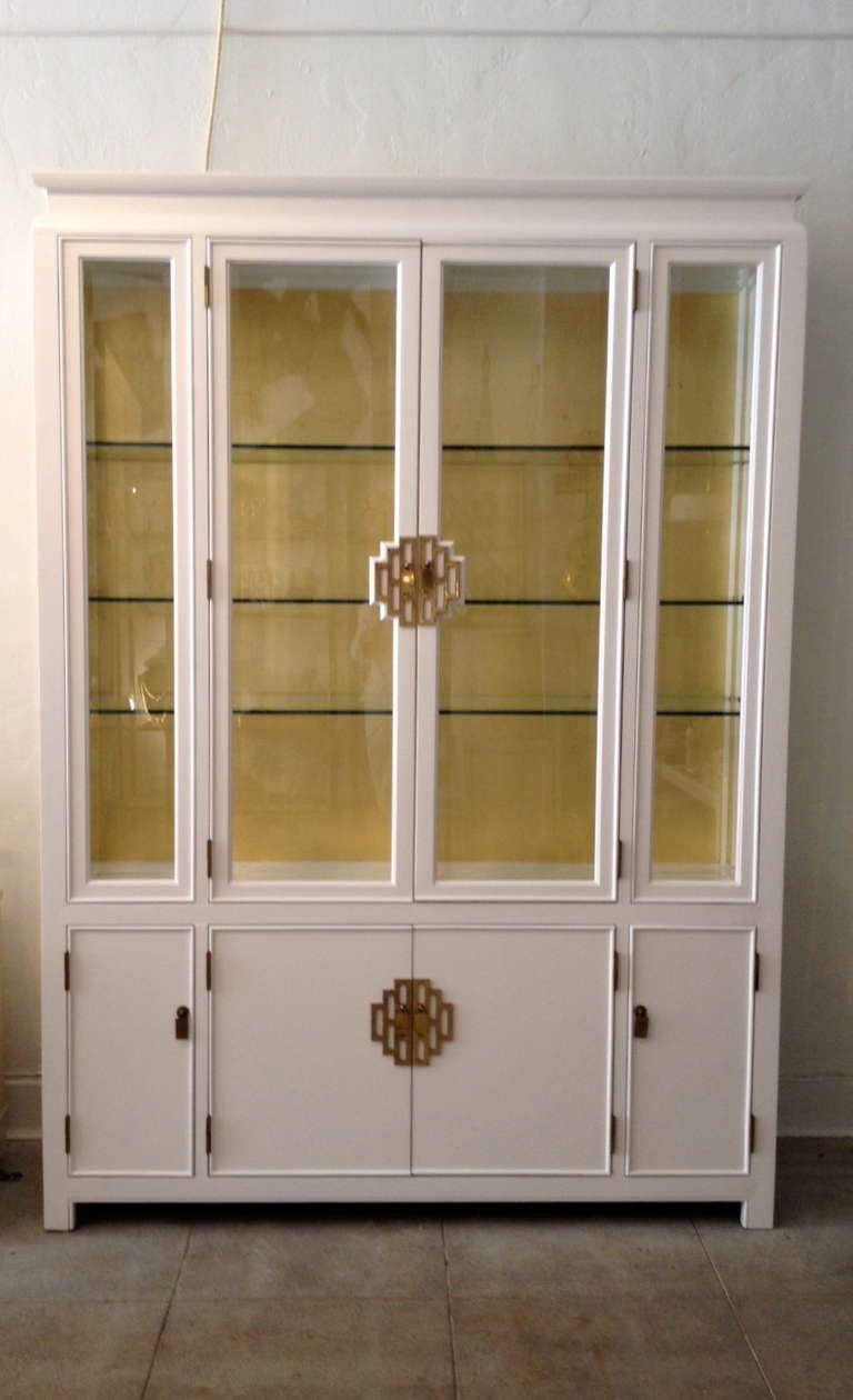 This beautiful mid-century style china cabinet is manufactured by Century Furniture Co.  It has been refinished in white and the interior is gold leaf.  There are six glass shelves in the display portion which are encased in the doors with beveled