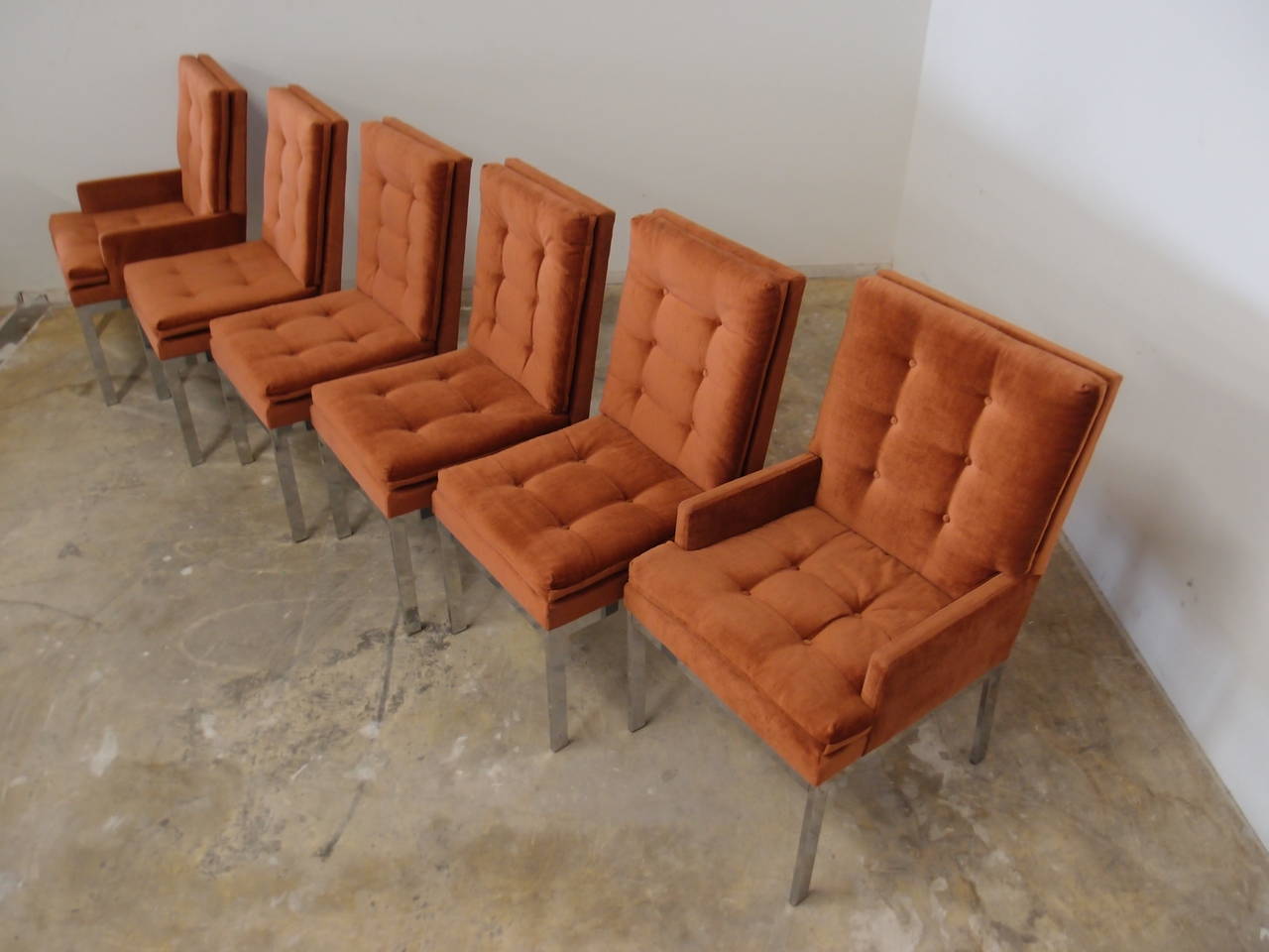 These set of six dining chairs manufactured by the Design Institute of American and attributed to Milo Baughman are comprised of two captain's chairs with arms and four chairs without arms. The original burnt orange color upholstery is serviceable