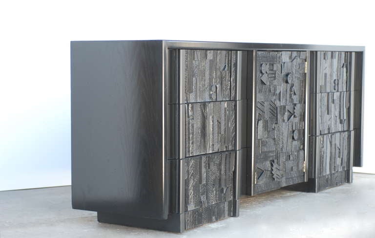 Reminiscent of Paul Evans work this Credenza or Dresser has been refinished in a rich black. This stunning piece was manufactured by Lane Furniture.   It has six drawers and two doors in the center which reveal two shelves.