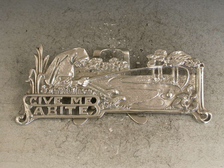 An interesting Edwardian pictorial cast silver Menu Holder in the Art Nouveau style depicting a Nun, Dame Juliana, fishing in a pond and pierced with the legend 