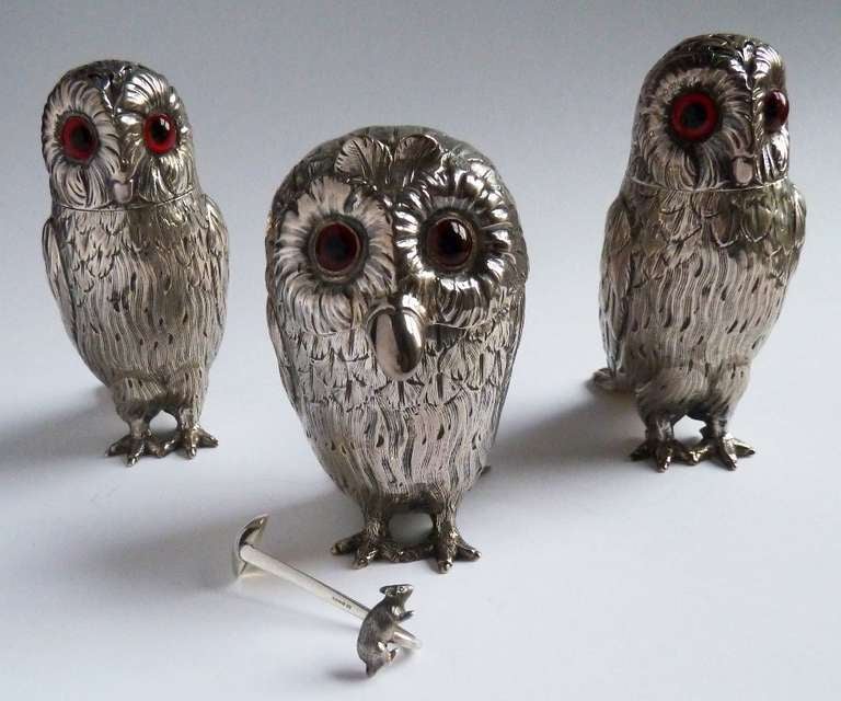 A very fine garniture or matched set of three Victorian silver Condiments, made in the form of Owls, consisting of a pair of Peppers and a Mustard Pot with associated modern silver Spoon with mouse terminal. Amber glass eyes.

The Mustard is by