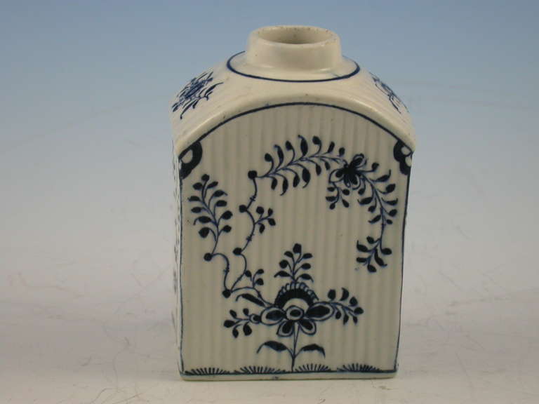A rare rectangular Lowestoft Tea Canister with sloping shoulders, a circular opening above a short cylindrical neck ( the cover lacking) and a flat rectangular base. Moulded with narrow vertical ribs and decorated in a formal floral design,