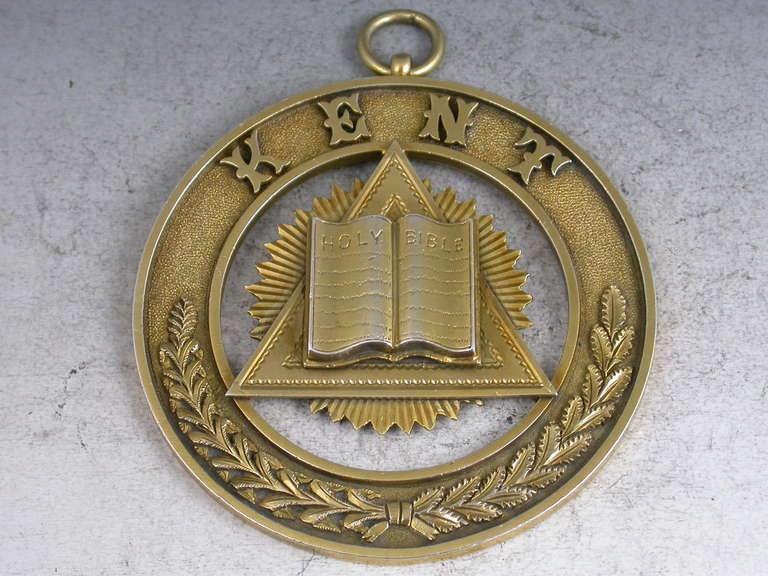 A Victorian silver gilt Masonic Badge / Medal depicting the Holy Bible on top of a triangle and rising sun, the border with a laurel wreath and the word 'KENT' on a matt back-ground, with attached suspension ring. 

By Charles Weeden, London, 1892