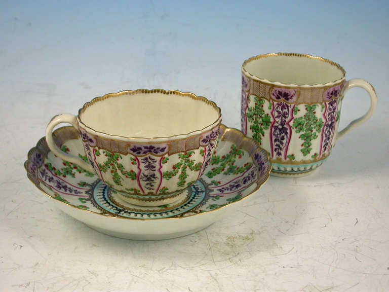 A very fine Dr Wall Worcester Trio of Coffee Cup, Tea Cup and Saucer of fluted form, from the lilac version of the Holly Berry / Hop Trellis Service after the Sevres original, painted with a flower spray in the centre surrounded by a turquoise