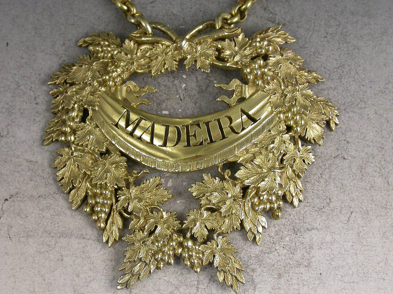 An extremely fine and large George III silver gilt wine label of opulent design in the form of a wreath of vine leaves with tied ribbon surmount, the pierced title Madeira on a banner across the label.

In good condition with no damage or