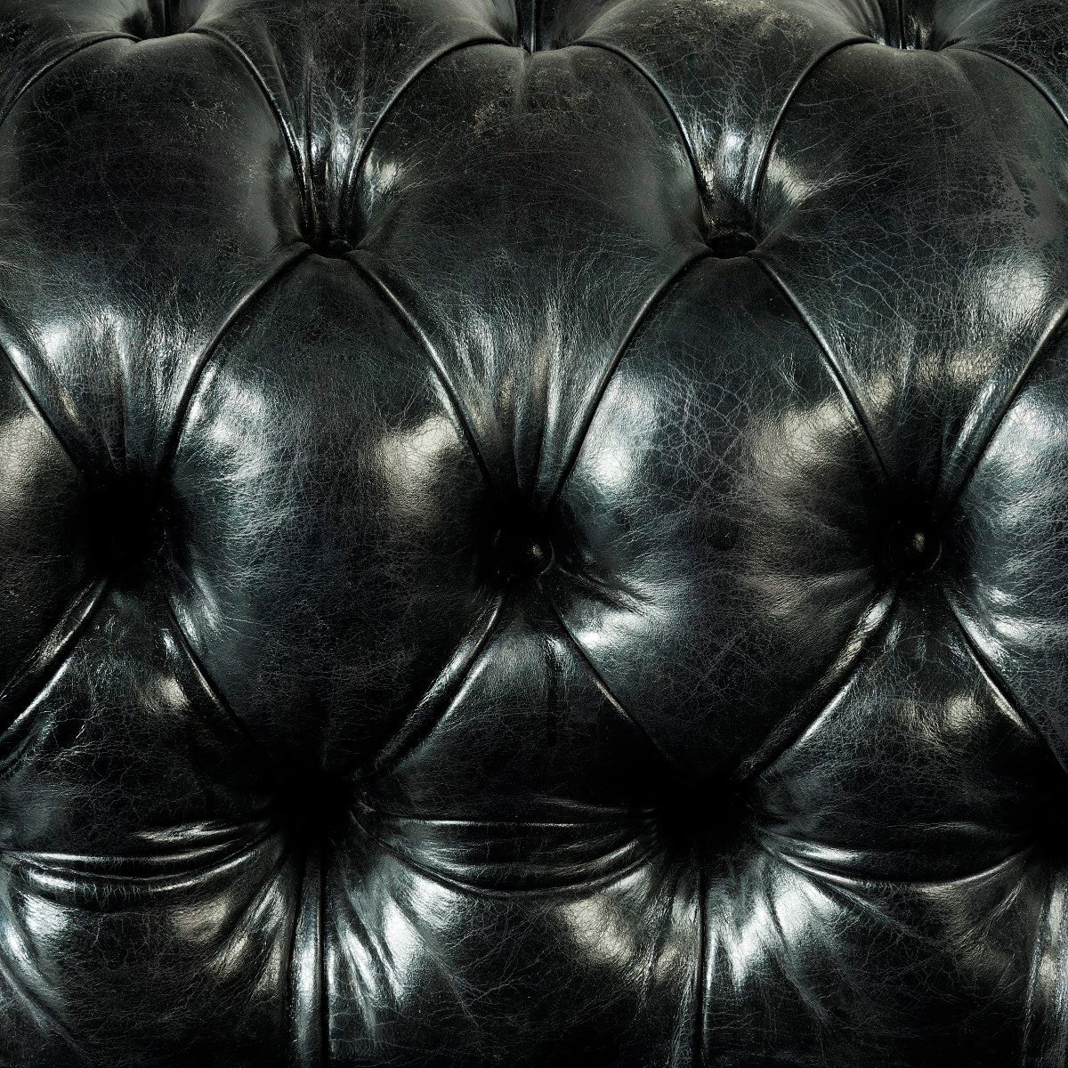 A pair of Chesterfield sofas by Shoolbred, of typical form, each reupholstered in deep-buttoned distressed black leather. The castors stamped Shoolbred, London. 

Seat height 14 1⁄2 in