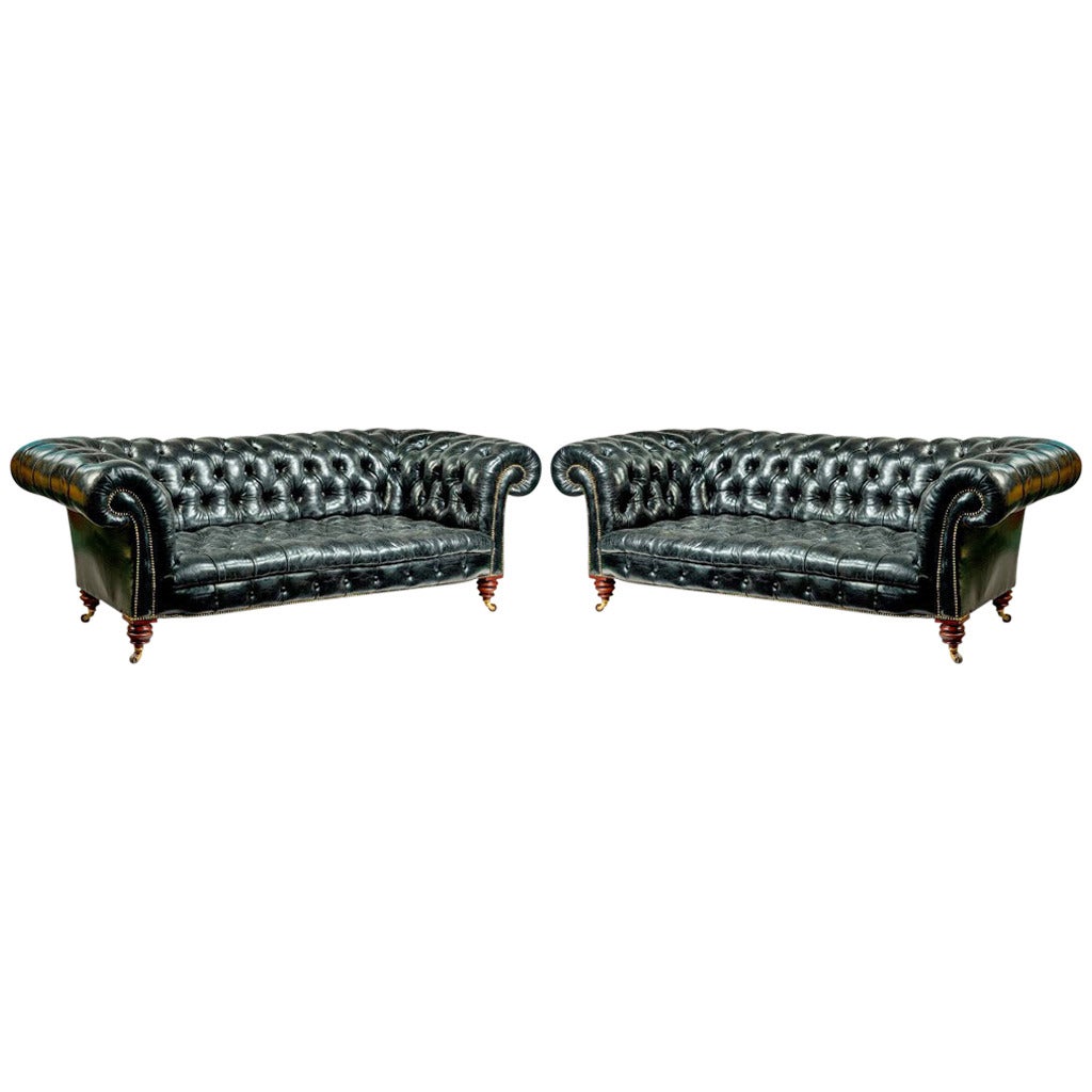 A pair of black leather Chesterfield sofas by Shoolbred