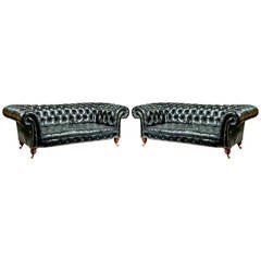 A pair of black leather Chesterfield sofas by Shoolbred