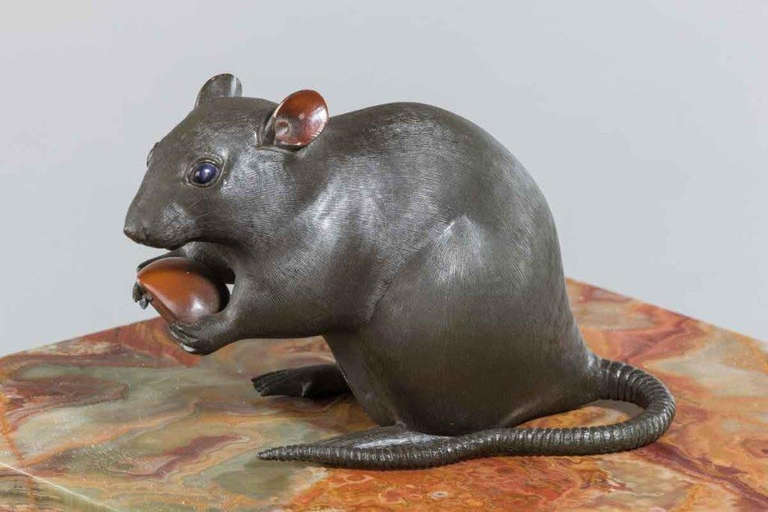 A Meiji period bronze of a rat holding a chestnut, signed in a gilt seal.