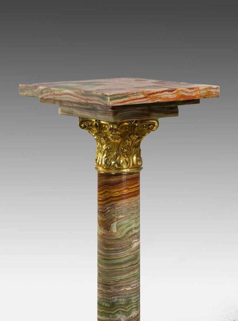 A pair of amber coloured African onyx columns with revolving tops and gilt bronze mounts.