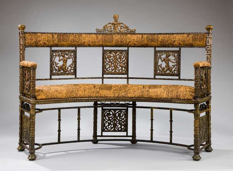 An antique curved wrought iron bench by Oscar BachT 
he high back has a central classical mask and panels of mermaids and mermen. The cresting, seat and arm rests are upholstered and there are areas of gilt bronze throughout. 

Literature: Oscar