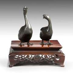 A pair of Meiji bronze geese stood upon a hard wood stand.