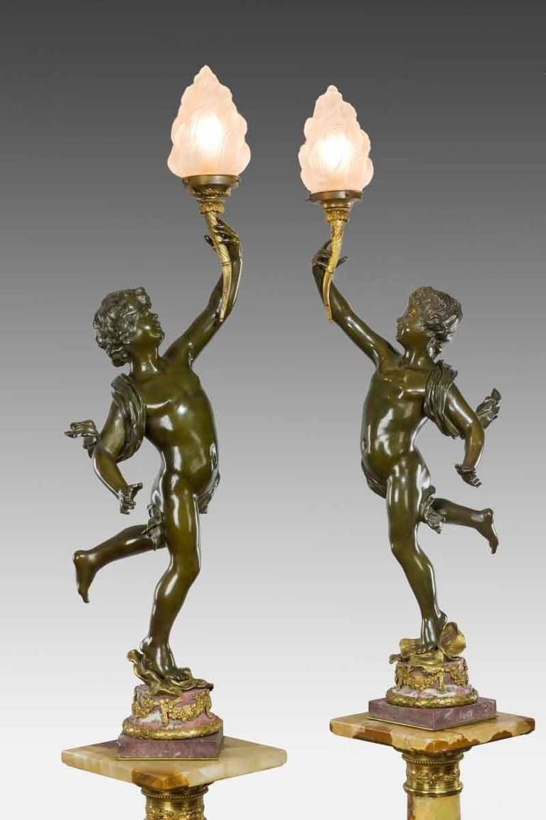 A fine pair of 19th century bronze figural lamps in the style of Moreau, with putti holding gilt cornucopia, raised upon ormolu mounted rouge marble bases.
