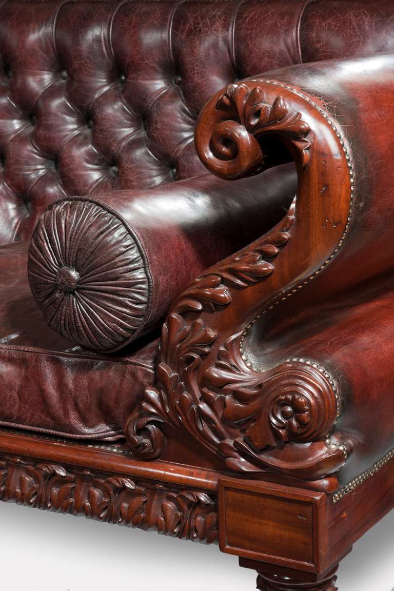 An antique Regency mahogany sofa 
This sofa has scrolling dolphin support arms and palmette carved legs and seat rail. Later upholstered in distressed burgundy leather.