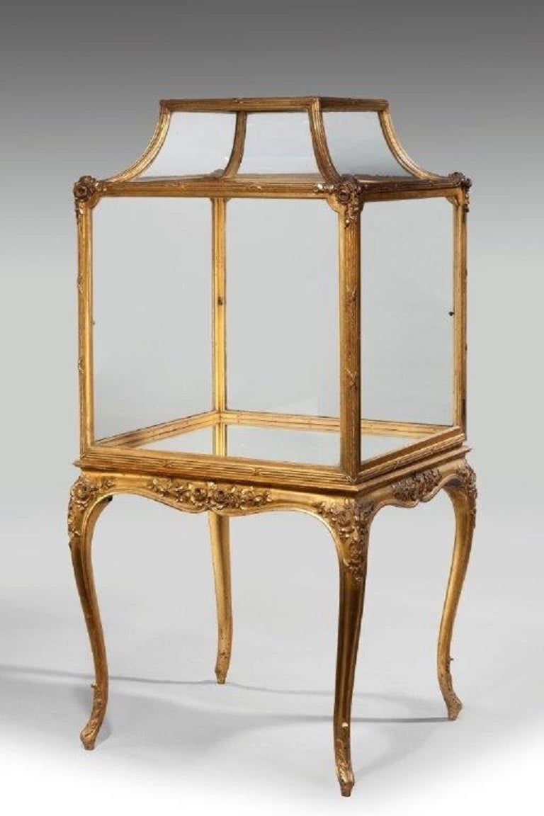 A rare giltwood free standing Napoleon lll square display cabinet, glazed throughout within a giltwood ribbon and reed frame, carved with rosebuds and raised on cabriole legs.