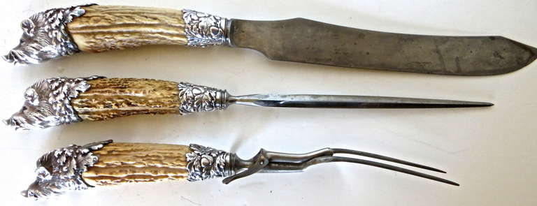 Very unusual fine quality three piece carving set; made of antler horned handles which end in a sterling silver figure of a Boar's Head. Red glass or perhaps jeweled eyes. The three pieces are comprised of a carving knife (16