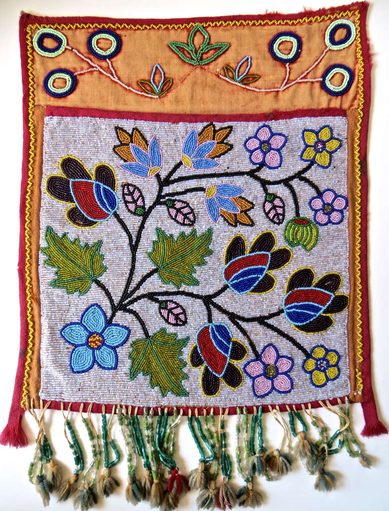This is a beautifully handcrafted native American bandolier beaded bag from the Great Lakes region, circa 1890. The heavily beaded bag with bright floral decoration is typical of the lake region, and was constructed by women utilizing thousands of