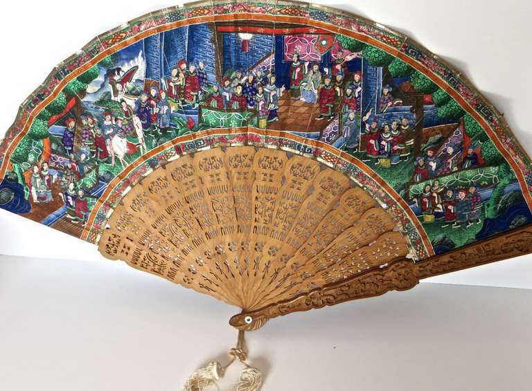 All original 19th century hand-painted on paper fan with applied pieces of ivory and applied pieces of silk to the faces of some people and scenary; with a hand carved sandlewood frame and sticks. The frame is carved with people and local fauna;