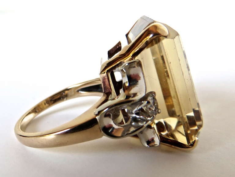This is a unique sized (approximately 20 carrots) citrine ring with round cut diamonds mounted in 14-karat white gold on each side of the stone. The shank and stone mount are 14-karat yellow gold.
The citrine stone is synthetic and measures 13/16