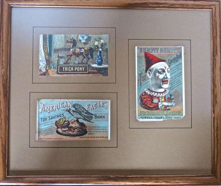 Five mechanical bank trade cards are displayed in two separate frames. In one frame are three polychrome trade cards, which the salesmen typically carried with them in a catalogue to show potential buyers examples of banks they had for sale.