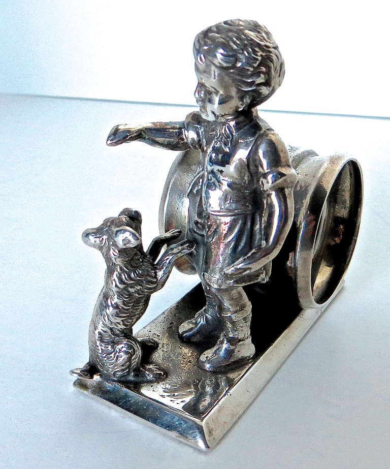 This is a much sought after Kate Greenway silver plated Victorian Napkin Ring, circa 1880. It depicts a young child giving a treat to a dog, and is modeled after the Victorian boys and girls who were featured and illustrated in children's books and