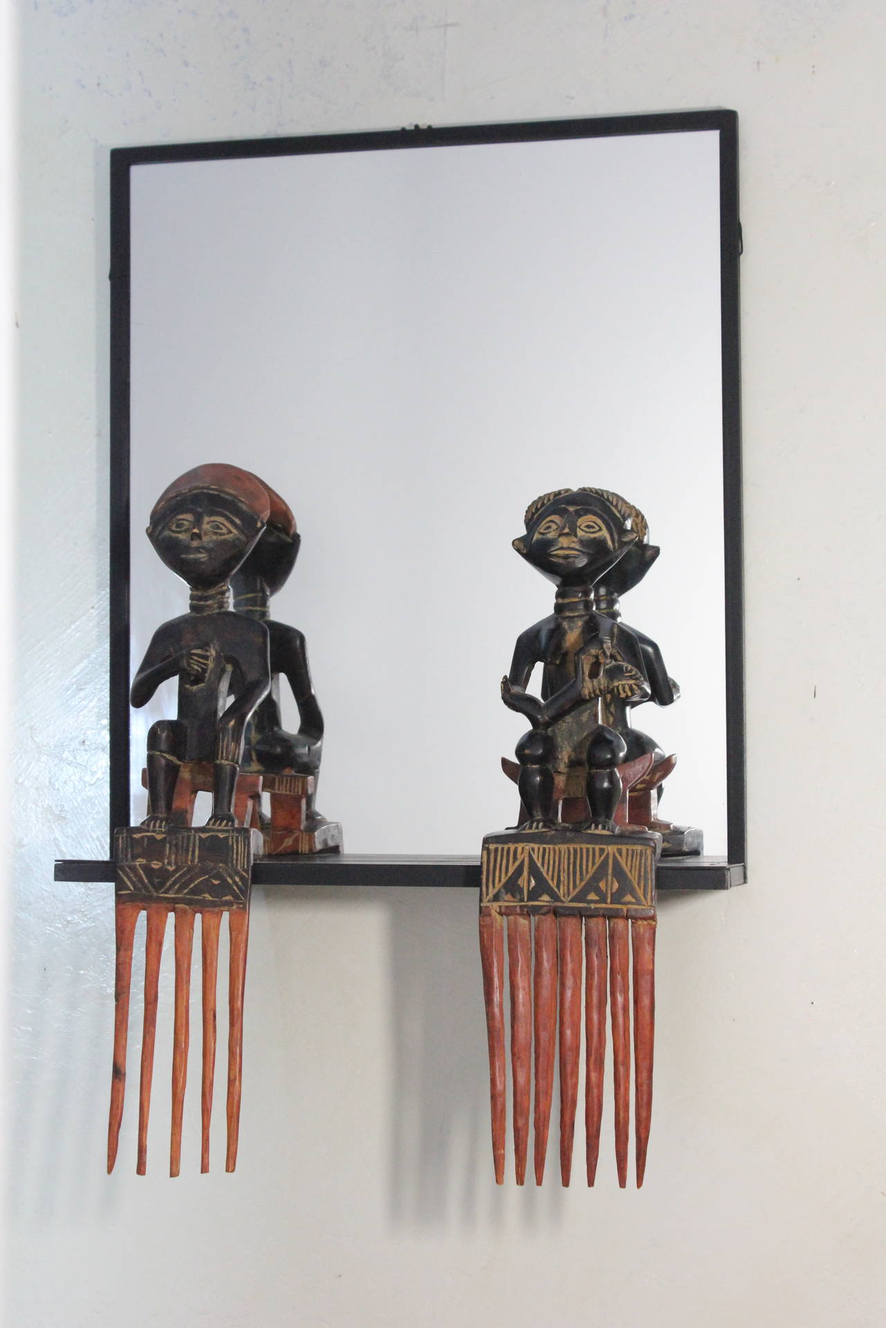 A one-of-a-kind black painted steel framed mirror with figural African comb
mounts, the figures are hand-carved and both different a very distinctive and exciting decorative object for your most interesting placement, 1970s.
Provenance: Assembled