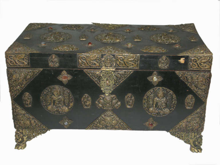 A very extraordinary, fabricated for a Maharaja or a very wealthy person, storage chest of black lacquered wood elaborately covered with brass buddhas, lion head end mounts, inlay round jewels and repousse chased brass feet, fabulously decorated on