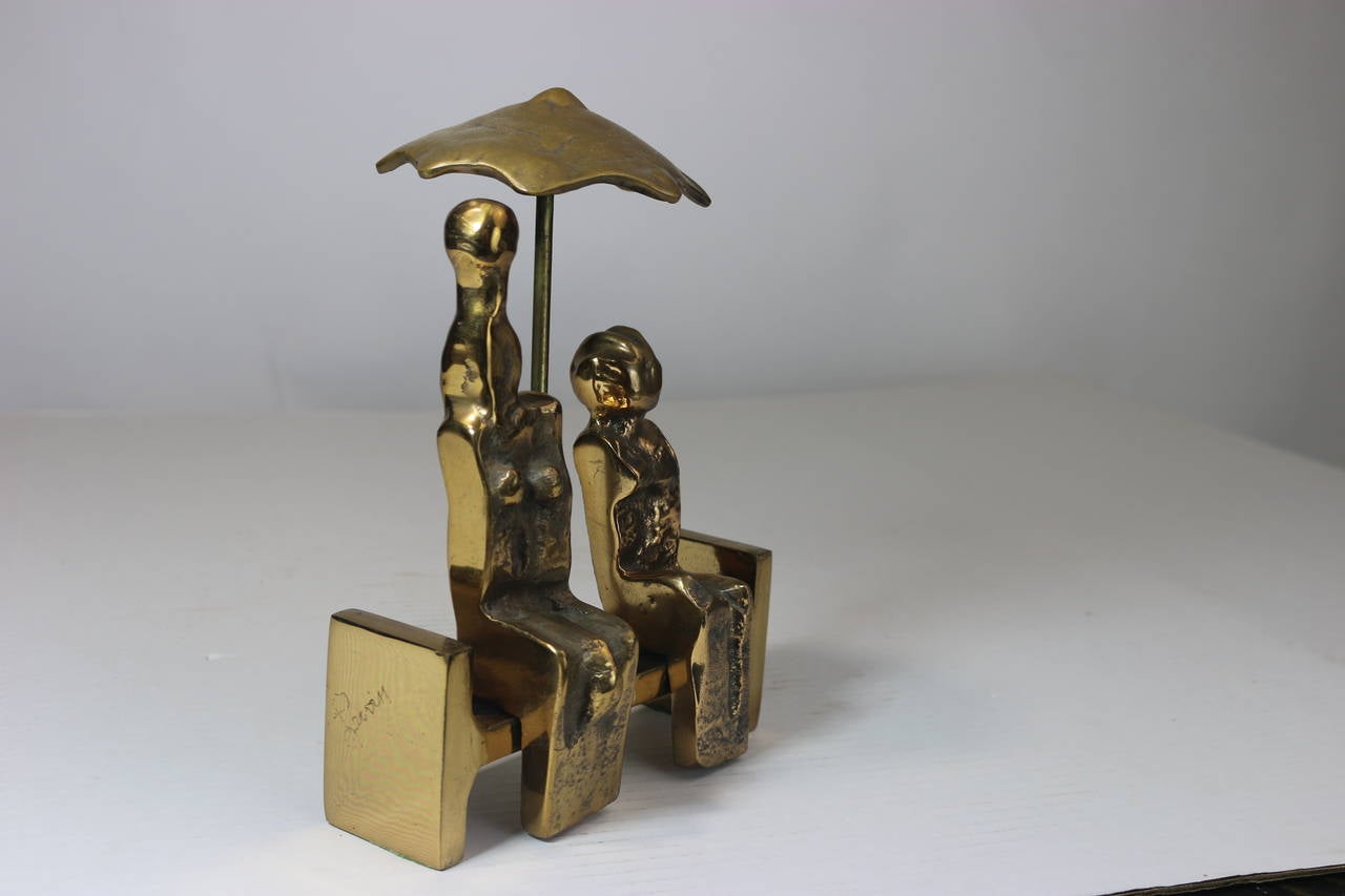 A very charming contemporary bronze sculpture 'Rendez-vous d'Amour', contemporary abstracted man and woman figures sitting on a bench under an umbrella with a polished gold finish in the style of Max Ernst.
Signed by the artist (indistinguishable