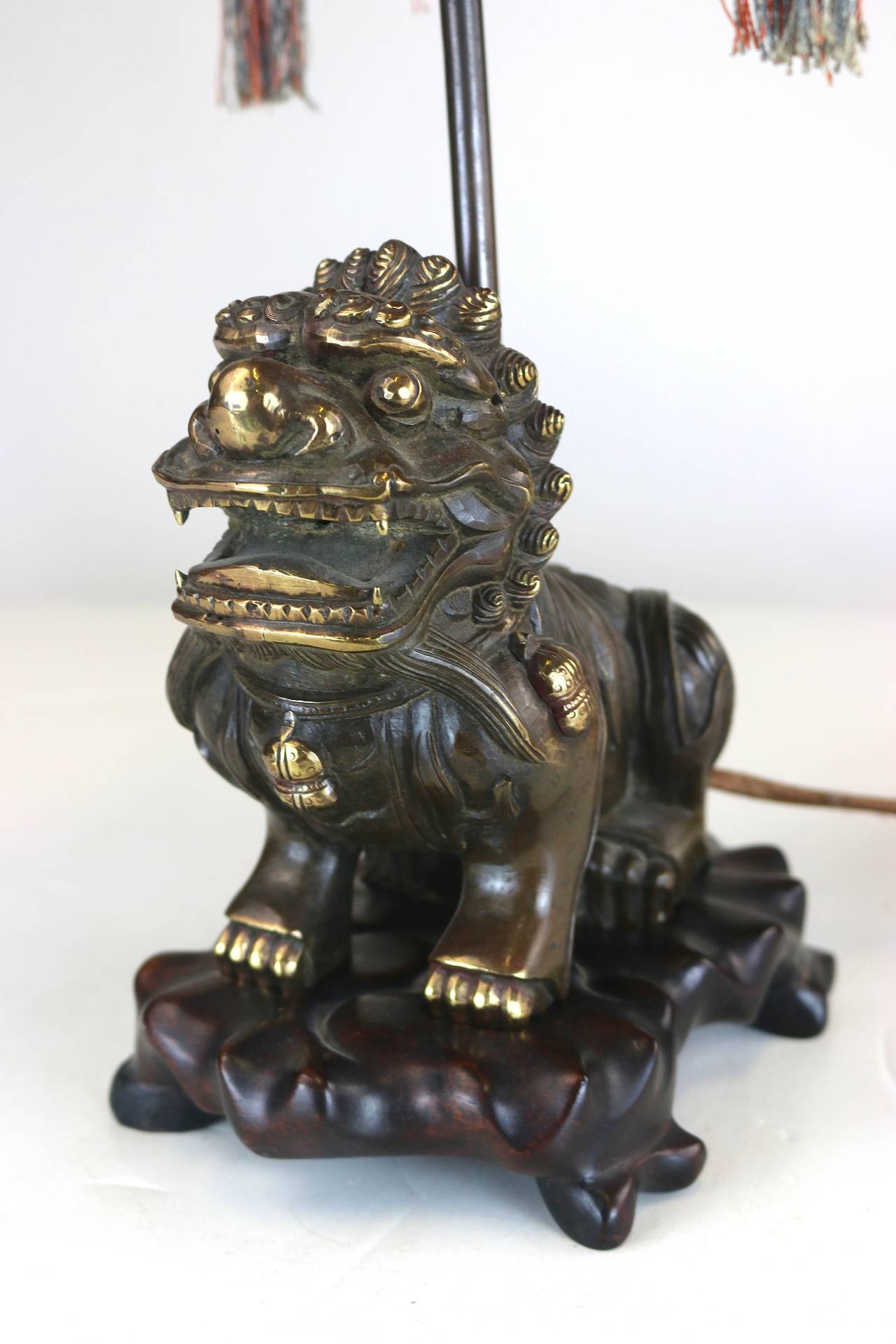 Extraordinary exotic 1920s one of a kind chinoiserie table lamp hand woven delicate beautifully designed exquisitely colorful pagoda shape tasselled shade with nicely aged patina brass/bronze foo dog on wood carved conforming base. With original