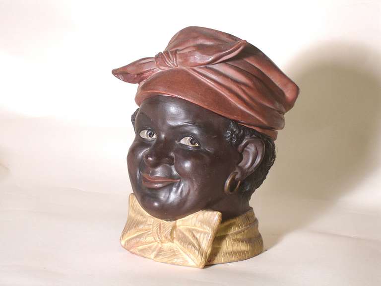 A rare Bernard Bloch black figural tobacco jar/humidor. Polychrome glaze decoration. A smiling man with sparkling eyes in a bowtie. The tied style hat is removable for tobacco access. The bottom is impressed bb '29 08, circa 1908.
Classic