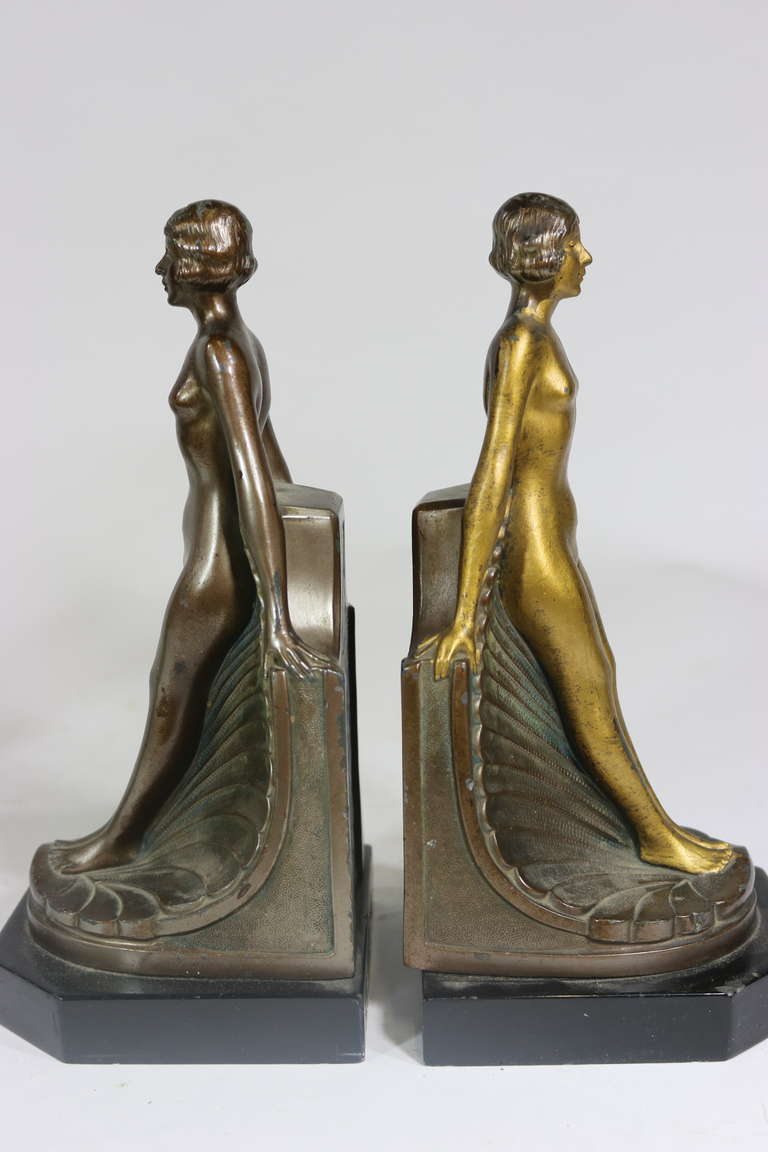Pair of 1930's Art Deco Sculptural White Metal Nude Ladies-One is Silver Patina one is Gold Patina Posing 'Out Of the Shell' Book Ends on a Black Marble Base. 
Other Distinctive Art Deco Book End Pairs are also Available--contact