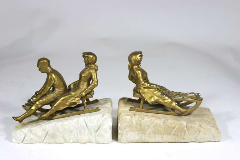 Pair of 1930s Art Deco bookends, a magical boy and two girls on Sleds mounted a marble carved base as frozen snow--gold patinated Spelter- A Charming Wintry Scene 'Frozen'--- 
There are three pairs of bookends available as per photo shown, for an