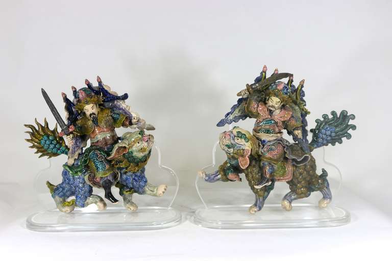 A Pair of Archaistic style Chinese roof tiles artistically Presented on a custom thick plexiglass lucite stand.
Two warriors on foo Lions in bold colors each brandishing a sword
one right facing/ one left facing.
Provenance-assembled from our