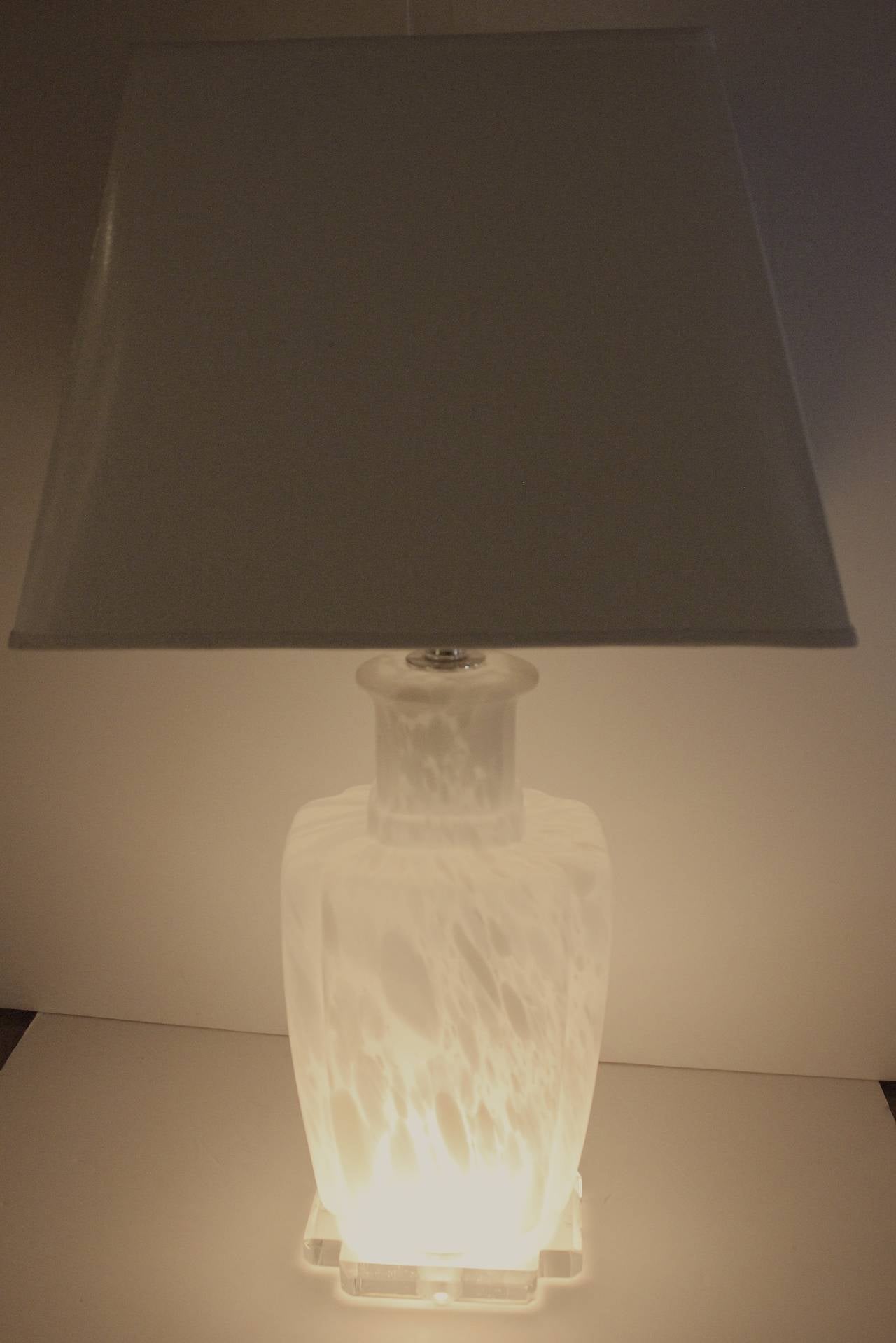 1960s chic Murano glass lamp on a polished clear Lucite base. Vase form body of white and clear gray marble pattern glass. Chrome stem, modern clear Lucite finial. The base lights up with a cord switch as well as the regular bulb under the shade-the