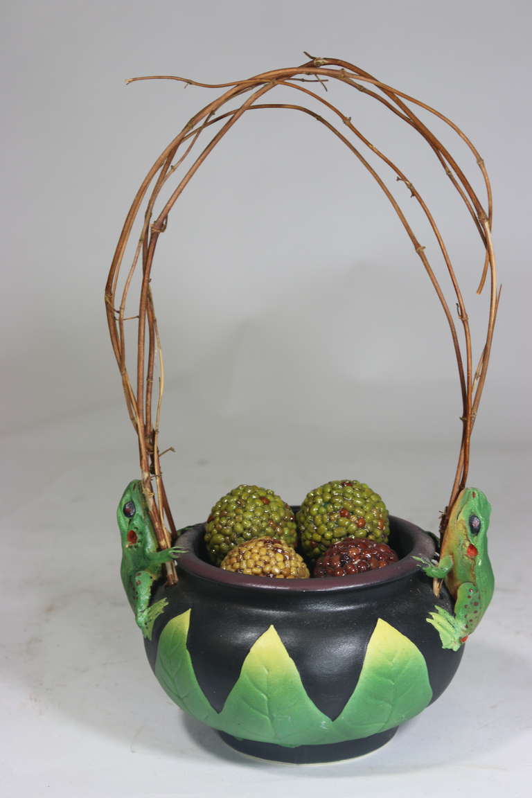 Modern Organic inspired artist fantasy vessel that will spark conversation!
Wheel thrown vintage porcelain vessel with hand incised leaf motif and hand crafted frog motif with a natural twisted twig vines handle. Airbrushed matte glazes fired to