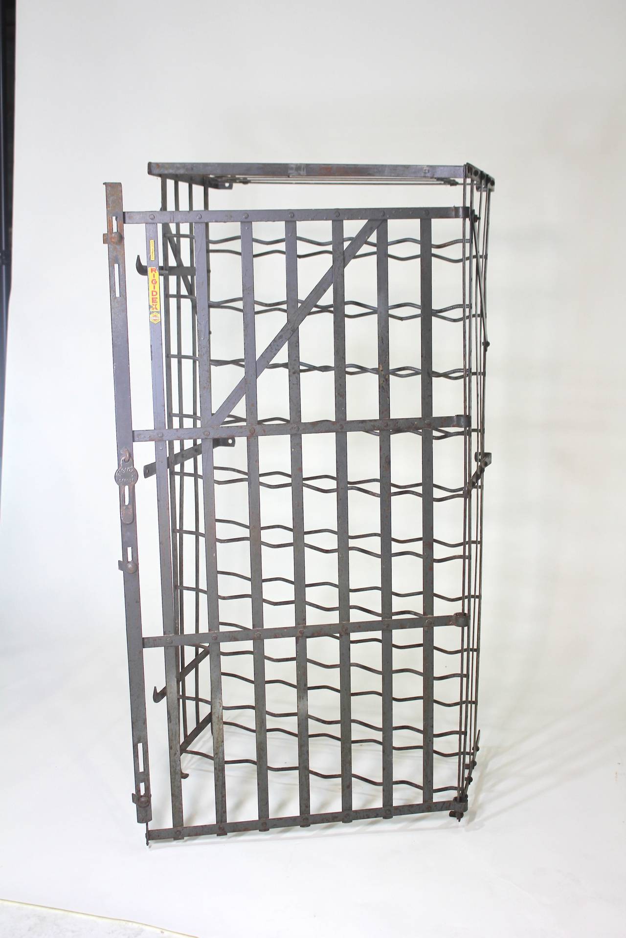A scarce French, 50 bottle Industrial liquor and wine rack safe holder, circa 1930s in steel with lockable door, with original cool yellow label Rigidex, made in France. There are installation flanges to the rear for fastening to the wall, just add