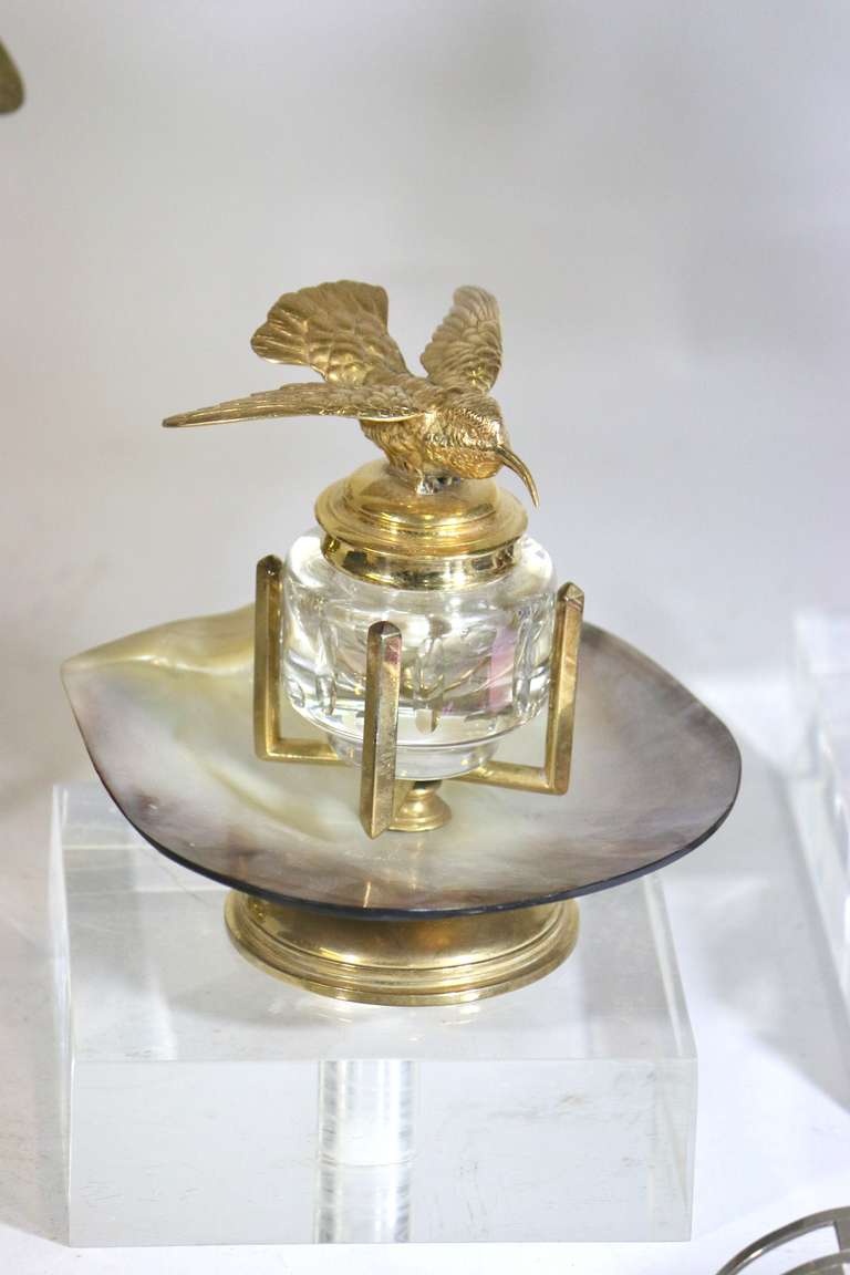 From the harkness library--an exquisite unique inkwell, a very finely detailed gold plated hummingbird as in flight, sits atop a hinge lidded inkwell of crystal mounted on a beautiful lustrous mother-of-pearl shell on a gold plated center pedestal.
