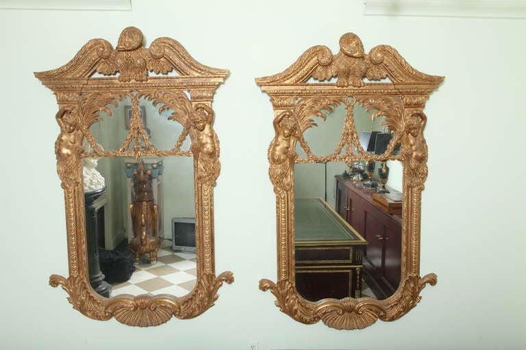 Impressive pair of mid century Federal Style mirrors. A dramatic pair of Large Mirrors. Carved water gilt wood frames with bas relief carved flanked putti figures and ornamentation, crested with a carved eagle. 42