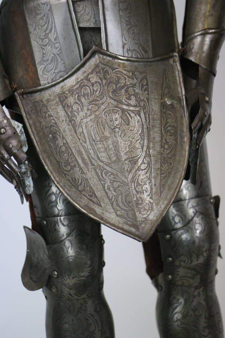 19th century or earlier Continental Medieval Militaria. A very distinguished pair miniature suit of armor, after a 17th century original. The complete engraved decoration on silvered steel suit, including helm, cuirass, pauldrons, rerebraces, elbow