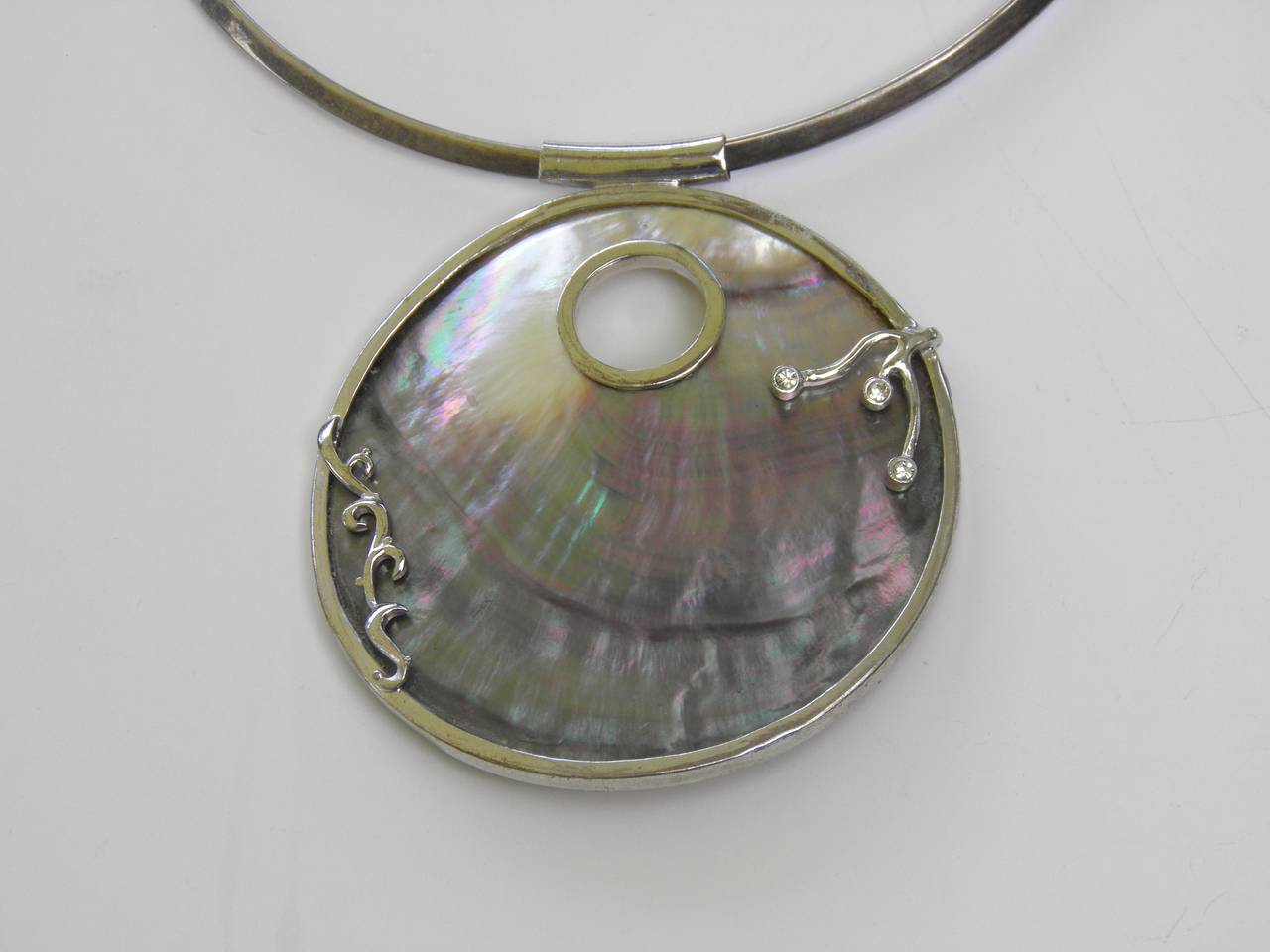 Beautiful sterling natural gray mother-of-pearl front/ivory mother-of-pearl back pendant with CZ framed coral shaped silver design on the amulet all on a sterling Collar Ring.
Brings forth thoughts of a dreamy day on the ocean to mind.

From the