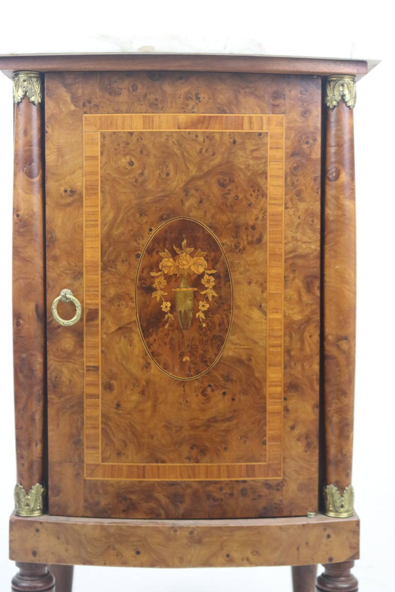 A very handsome Louis XVI style mellow elm burl and walnut cabinet with single door opening to a top drawer and shelf interior with a carrara marble top. Colorful floral inlay, brass Ferrule leg trim and columns with ormolu leaf trim--Elm Burl Wood