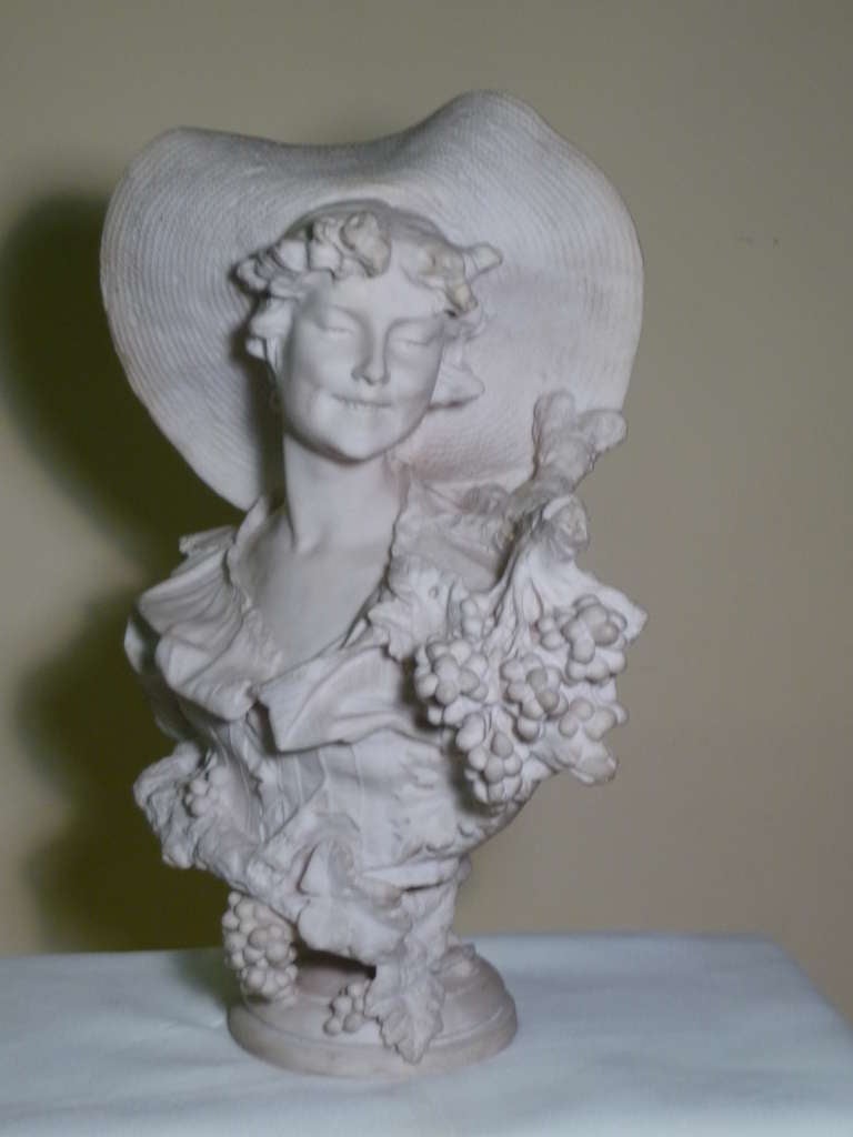 This is a 30” h White Marble composition Bust of A Sumptuous Beautiful Lady with an Enigmatic Smile in a Peasant Blouse with A Large Sun Hat With Grape Clusters and Vines After Famed Italian Sculptor Caesare Lapini 1895 in his Florence Italy Gallery