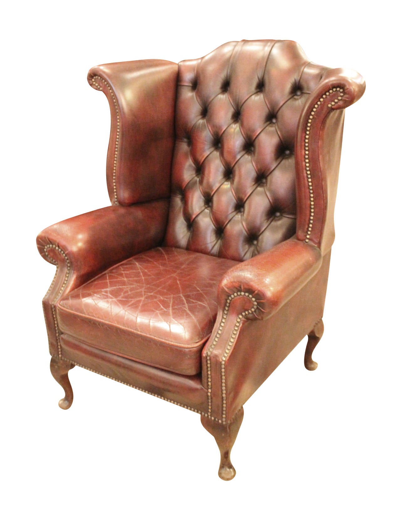 1980s pair of English tufted leather wingback chairs with claw feet. These chairs are in very good condition for their age with only minor cracking in the leather. The leather is a rich dark red color and is rivets with brass rivets around the arms