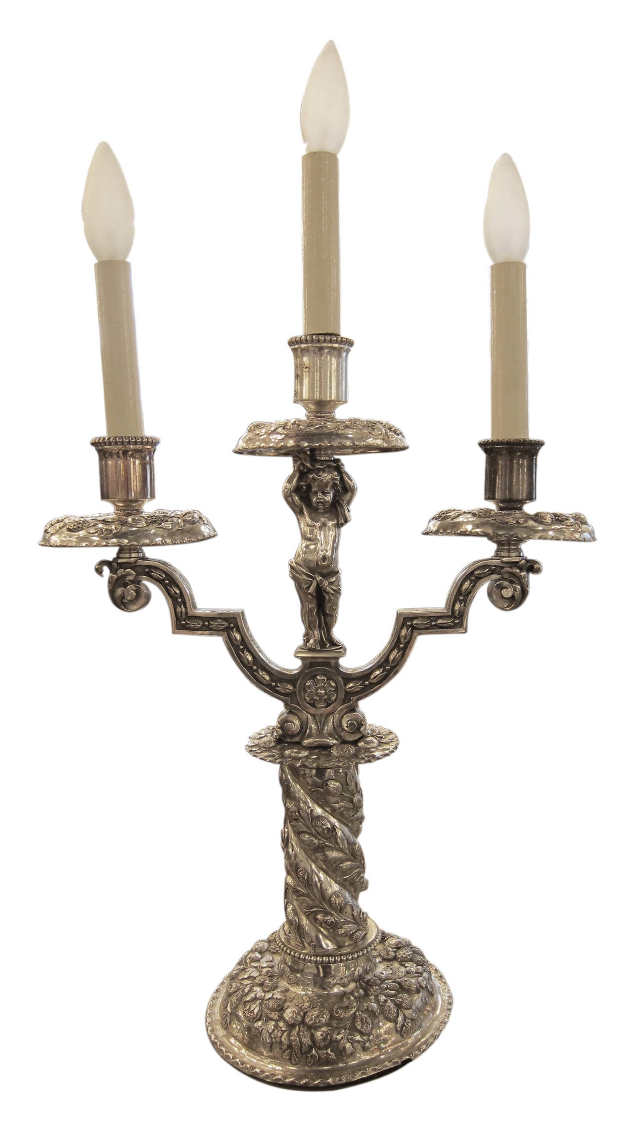 1900s pair silvered bronze table candelabrum with opposing cherubs made by  EF Caldwell. One lamp is slightly bent at base. This can be seen at our 2420 Broadway location on the upper west side in Manhattan.