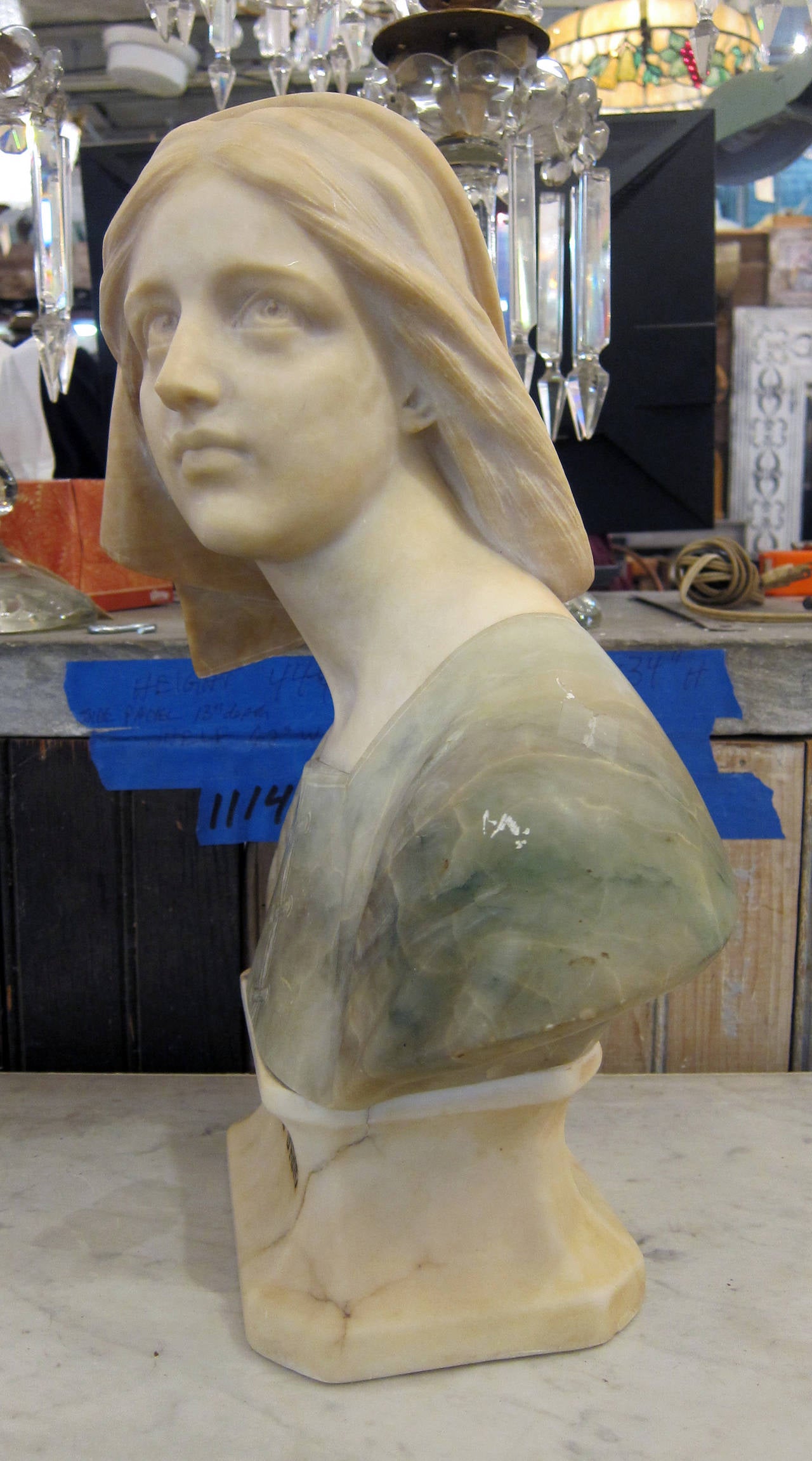 Light blue alabaster and white marble make up this bust of Joan of Arc. Carved on the bust is 