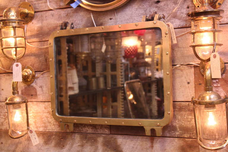This is a rectangular bronze porthole mirror with hinges salvaged from a ship. This can be seen at our 400 Gilligan St location in Scranton, PA.