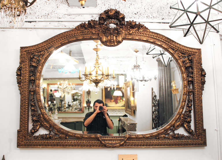 1940s floral overmantel mirror with beveled glass. Spectacular gilded detail. This can be seen at our 2420 Broadway location on the upper west side in Manhattan.