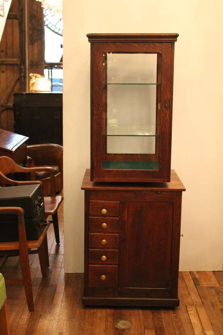 Beautiful oak display cabinet with two glass shelves. This unit also revolves for easy viewing of merchandise or collectibles. Bottom of the display portion has green felt. There are five small locking drawers beneath for storage as well as a small