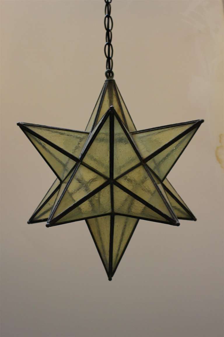 Amber glass hanging electric star lamp. This star hangs from a black chain and has a matching black canopy. Some minor cracks in glass. This can be seen at our store on Union Square at 5 East 16th St. in Manhattan.